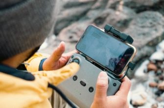 Оператор БПЛА со смартфоном и пультом от дрона DJI.