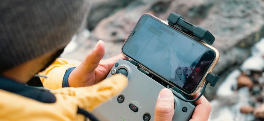Оператор БПЛА со смартфоном и пультом от дрона DJI.